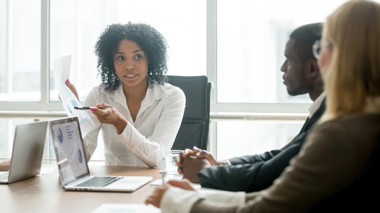 A woman explains a graph to two colleagues.