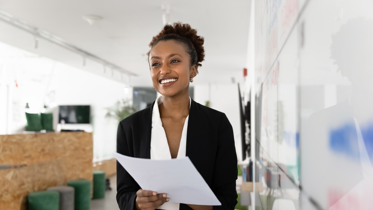 Young female employee smiling, holding paper