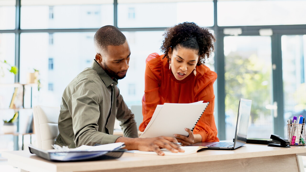 Two employees looking at paperwork, choosing, talking