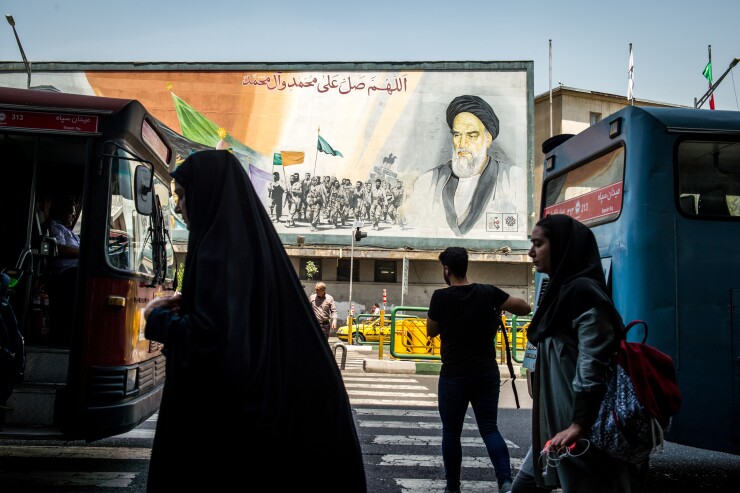Pedestrians pass in front of a political mural in Tehran depicting Ruhollah Khomeini, founder of the Islamic republic of Iran.