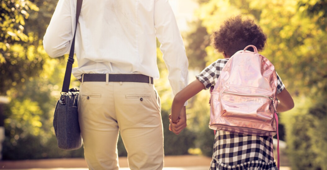 Father holding daughter's hand on the way to school; work bag; outside