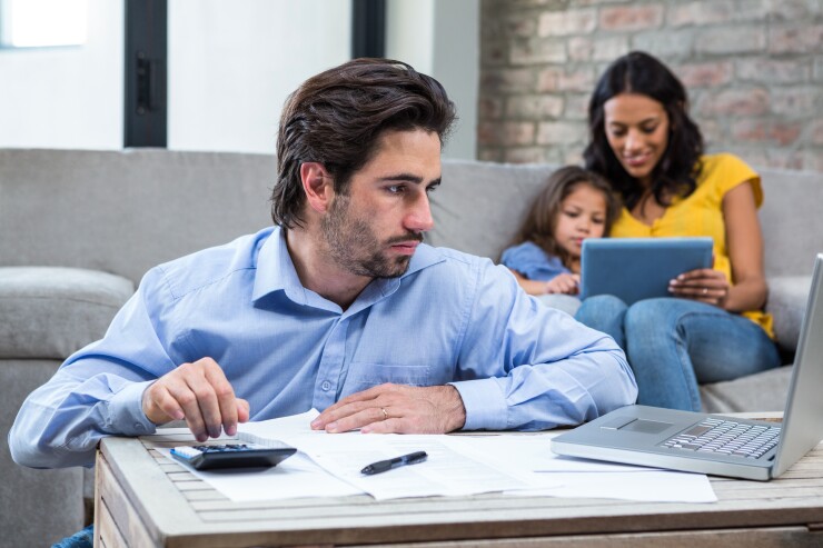 Family in apartment, dad looking at computer, paying bills