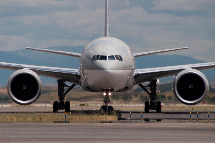 A Boeing 777 on the runway with mountains in the background.