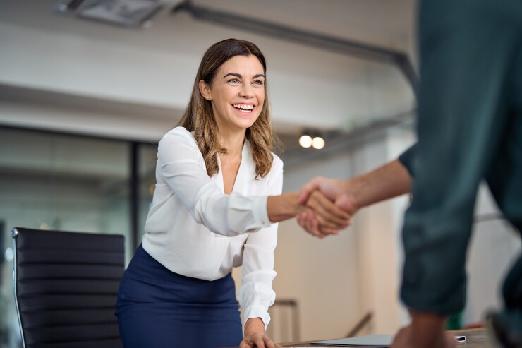 A woman shakes hands with her boss.