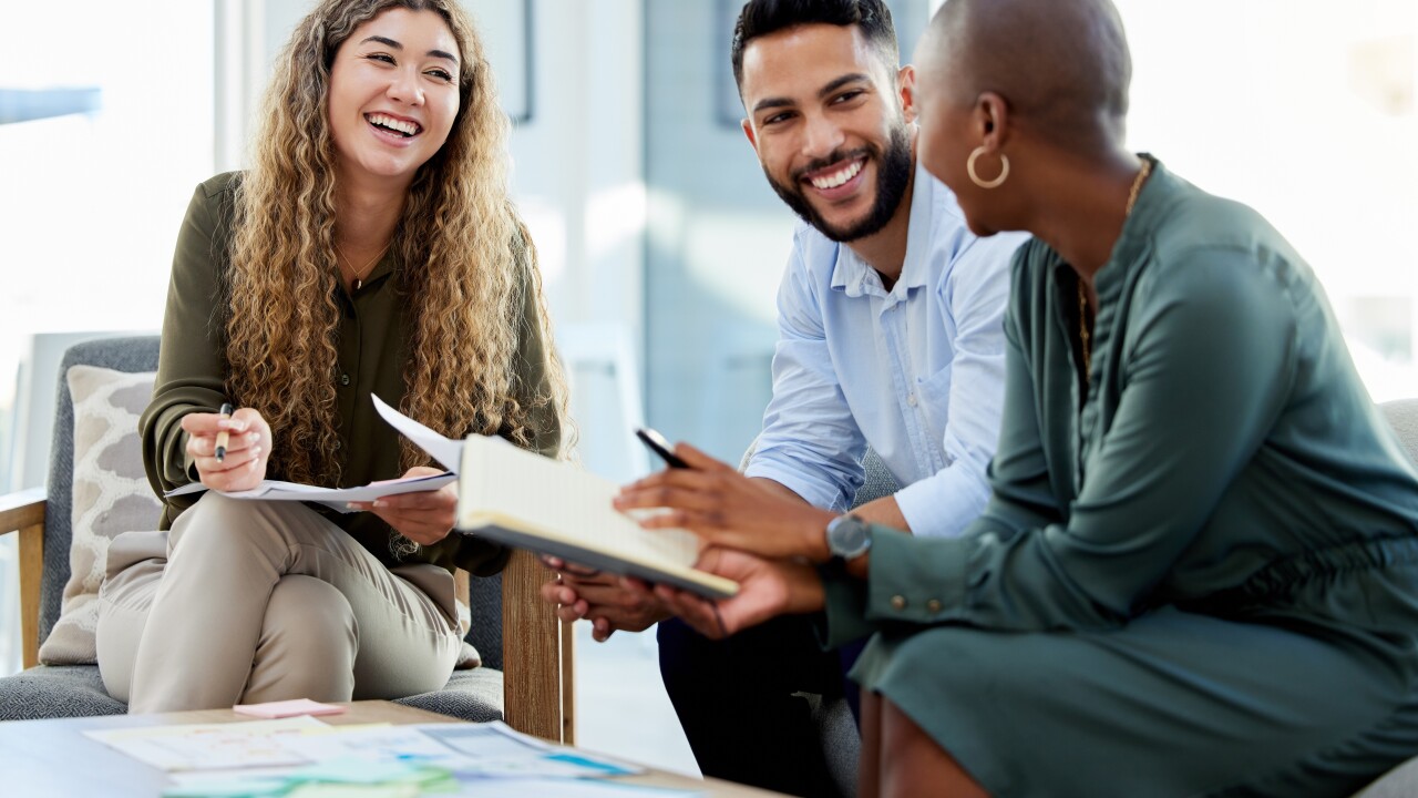 Three employees sitting and talking, smiling