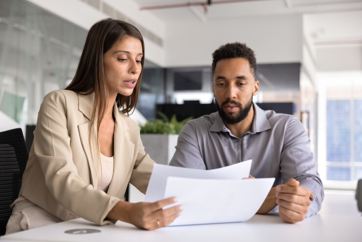 Two employees talking, looking at paperwork, helping