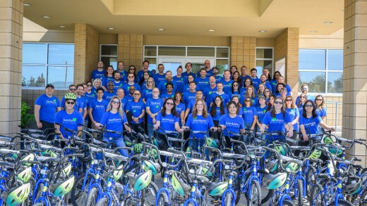 About 60 Bamboo employees in blue shirts behind rows of bicycles