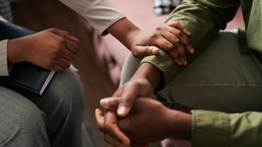 A person sitting down consoling another person.