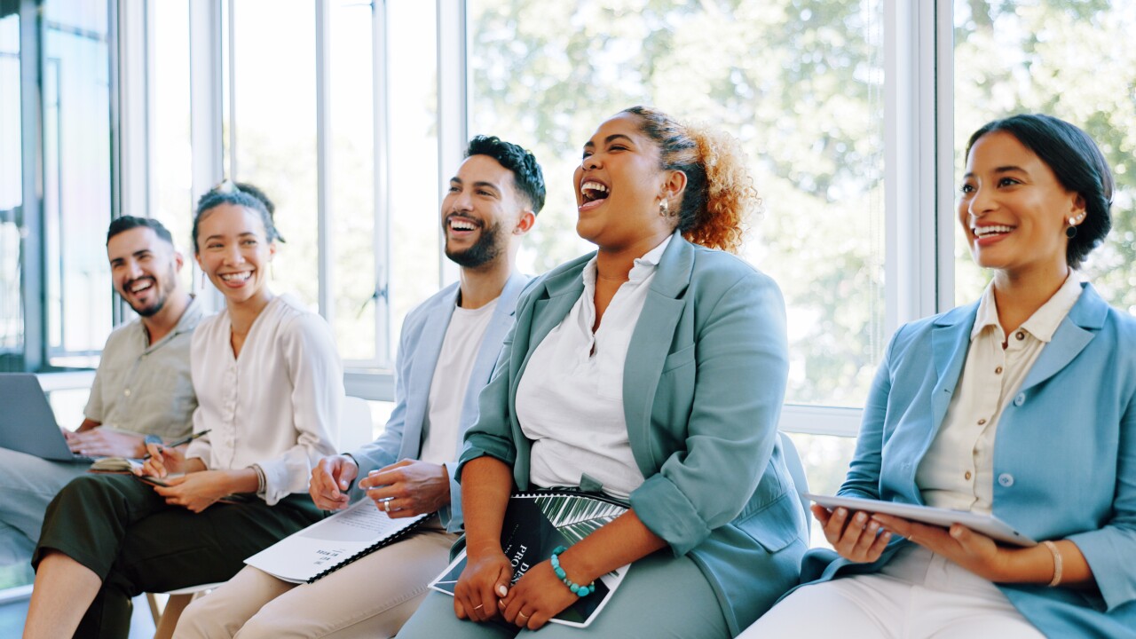 Line of employees sitting, laughing, smiling