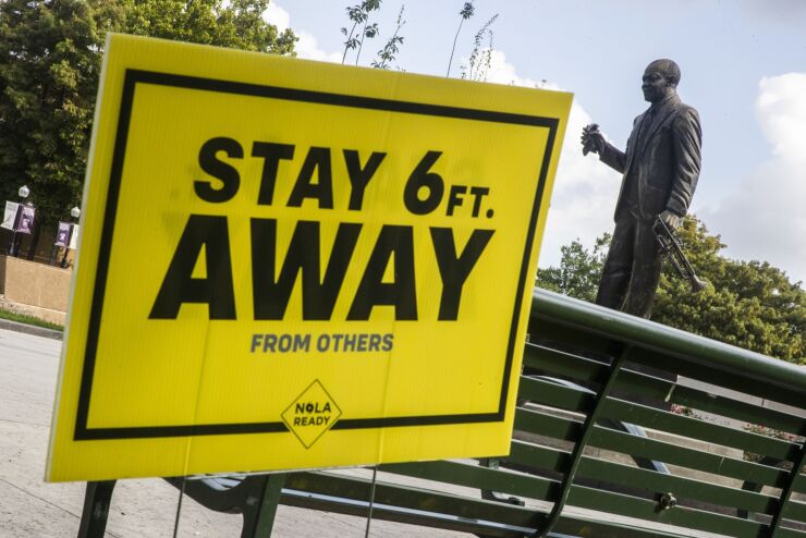 A sign reminding people to social distance stands at Louis Armstrong Park in New Orleans, Louisiana, U.S., on Wednesday, July 15, 2020. Many places that suffered most in the first wave of coronavirus infections including Louisiana are seeing case counts climb again after months of declines. Photographer: Sophia Germer/Bloomberg