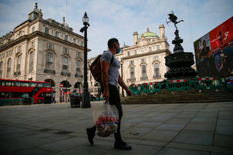 A pedestrian carries a Tesco Plc shopping bag in view of the Statue of Eros in Piccadilly Circus in London, U.K., on Friday, Sept. 11, 2020. Britain recorded strong economic growth in July as coronavirus restrictions eased, but mounting job losses and the risk of a messy Brexit are threatening a turbulent end to the year. Photographer: Hollie Adams/Bloomberg