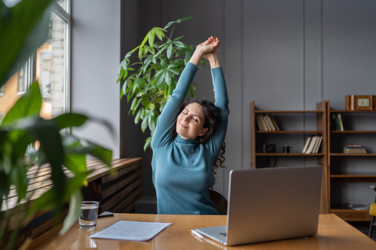 Woman stretching at desk, looking at peace