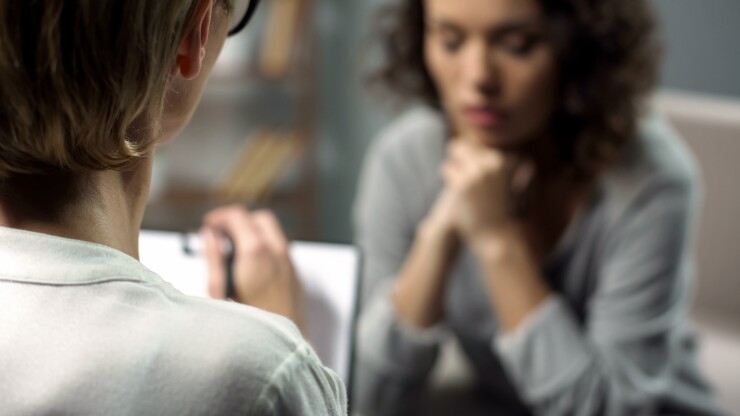 A health professional takes notes while talking to a woman.