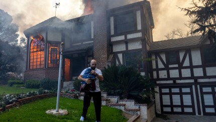 Resident carries flag outside of burning house