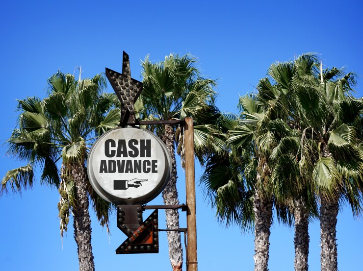 Image showing weathered sign in front of palm tress that says "CASH ADVANCE."