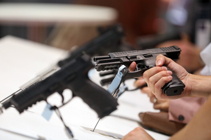 An attendee holds a pistol during the Defense and Security Equipment International exhibition at Excel in London.