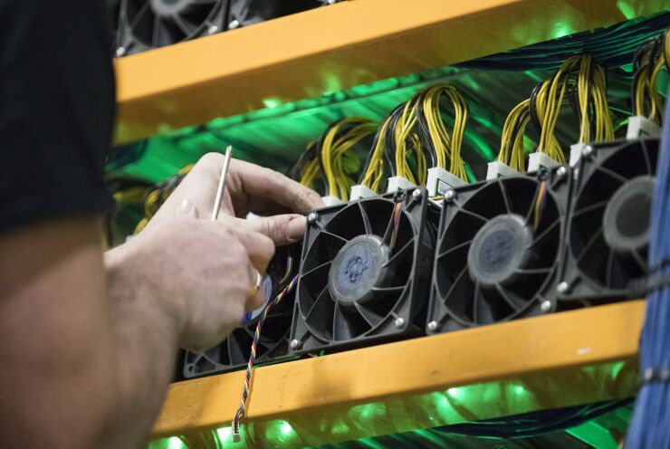 A worker changes the fan on a miner, the computing power to the cryptocurrency farming operation seen at Bitfarms in Farnham, Quebec, Canada, on Wednesday, January 24, 2018. Photographer: Christinne Muschi/Bloomberg