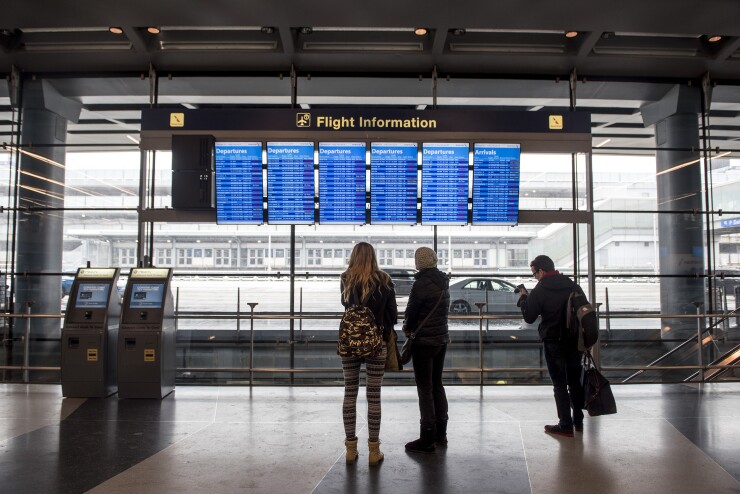 Travelers view American Airlines Group Inc. departures boards at O'Hare International Airport (ORD) during a snow storm in Chicago, Illinois, U.S., on Friday, Feb. 9, 2018.