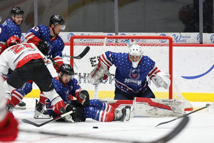 Hockey goalie blocks the net while players battle for the puck in front of him