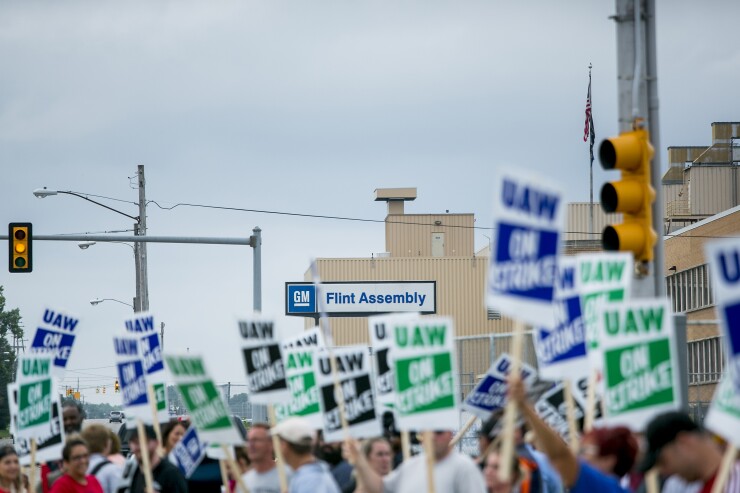 Demonstrators hold signs during a United Auto Workers (UAW) strike outside the General Motors Co. Flint Assembly plant in Flint, Michigan, U.S., on Monday, Sept. 16, 2019.