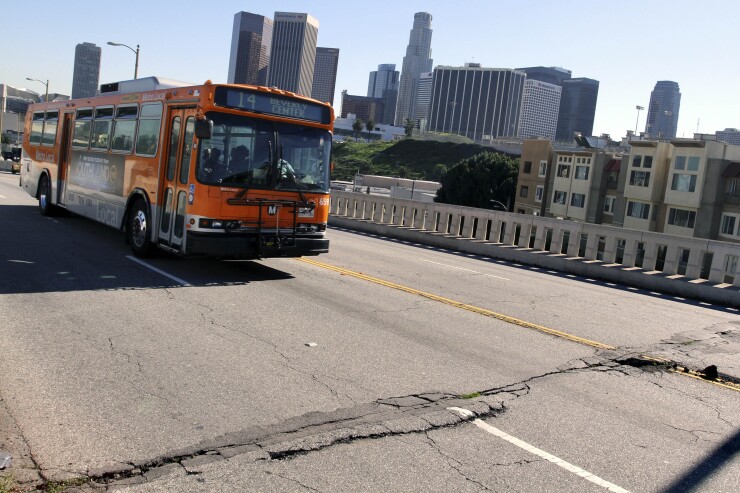 A bus drives past potholes and broken asphalt on West 1st Street in Los Angeles, California, U.S., on Friday, Jan. 21, 2011.