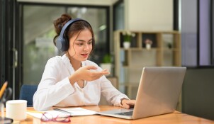 Woman wearing headphones while working on computer
