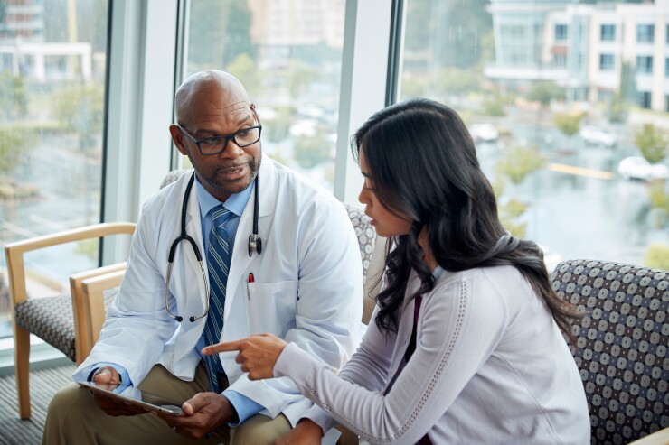 Woman talking to male doctor sitting in chair