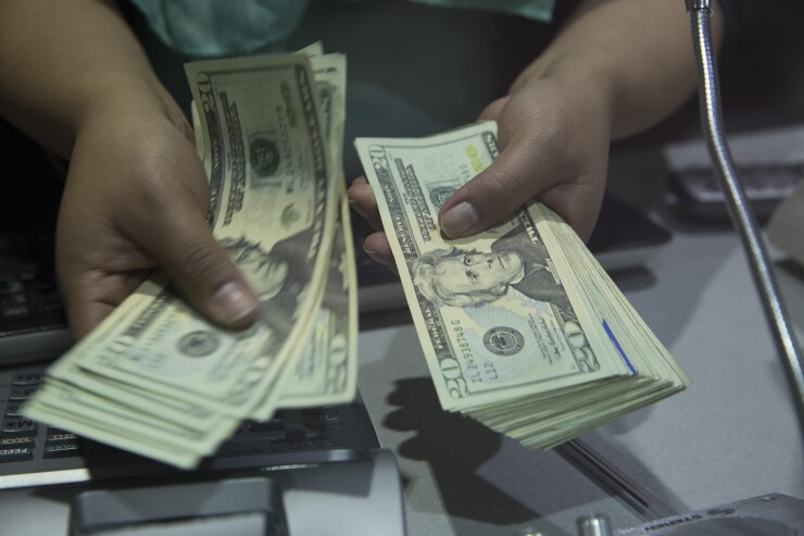 A worker counts U.S. twenty dollar bills inside a currency exchange store at the Benito Juarez International Airport in Mexico City, Mexico, on Monday, Feb. 15, 2016. Mexico's peso led world gains, climbing the most in more than four years, as Banxico was said to sell dollars directly to banks to support the currency. Photographer: Susana Gonzalez/Bloomberg