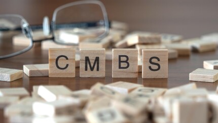 the acronym cmbs for commercial mortgage backed securities word or concept represented by wooden letter tiles on a wooden table with glasses and a book