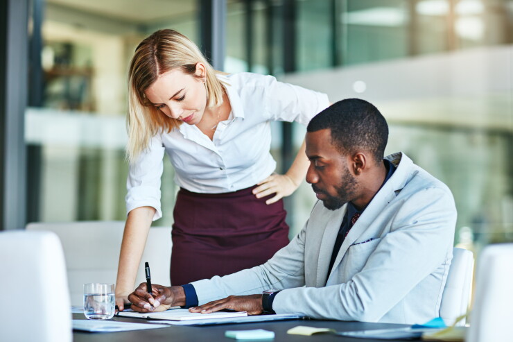One employee helping another with paperwork