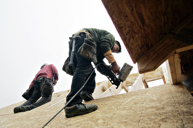 A carpenter uses a nail gun as he installs plywood on the roof of a home under construction in Garner, North Carolina.