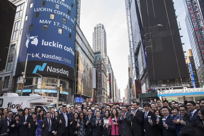 Jenny Qian Zhiya, chief executive officer of Luckin Coffee Inc., center, and Charles Zhengyao Lu, chairman and founder of Luckin Coffee Inc., center right, stand for photographs with employees in Times Square after ringing the opening bell during the company's initial public offering (IPO) at the Nasdaq MarketSite in New York, on Friday, May 17, 2019.