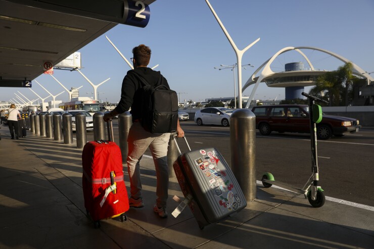 A traveler pulls baggage past a Lime scooter on the departures level in front of the Theme Building at Los Angeles International Airport (LAX) in Los Angeles, California, U.S., on Thursday, Oct. 25, 2018.