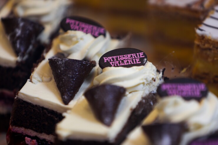 The Patisserie Valerie logo on cakes in a window display.
