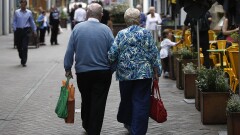 An elderly couple walk arm-in-arm past an outdoor cafe terrace in Edinburgh, U.K., on Wednesday, July 31, 2013. The latest opinion polls show supporters of Scottish First Minister Alex Salmond's campaign for independence lagging behind those in favor of the status quo by more than 20 percentage points ahead of the Sept.18, 2014, referendum. Photographer: Simon Dawson/Bloomberg