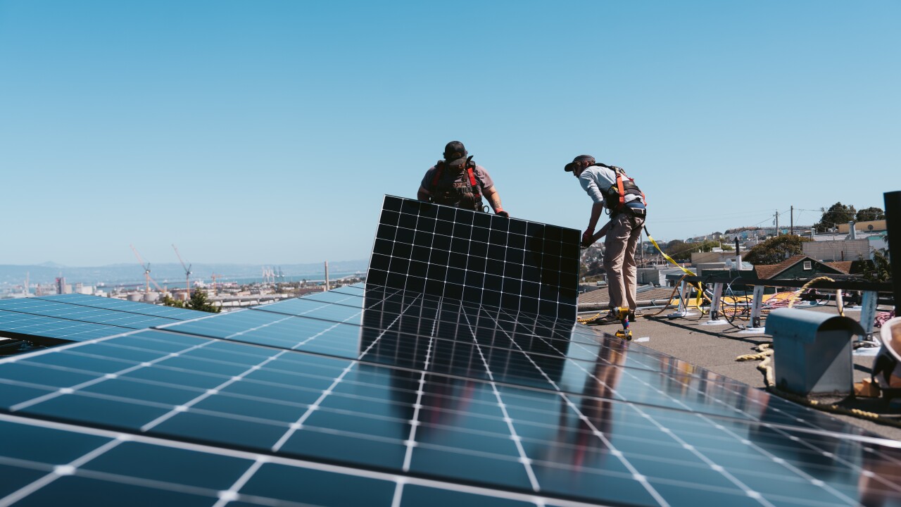Workers install solar panels at a home in San Francisco.