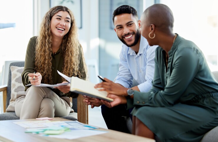 Three employees sitting and talking, smiling