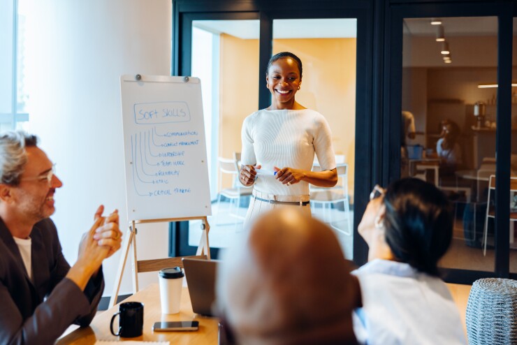 Woman standing in front of group, teaching, speaking