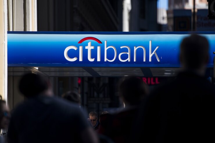 Pedestrians walk under signage at a Citibank branch in San Francisco.