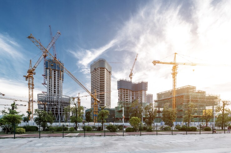 Several construction cranes in front of large buildings.