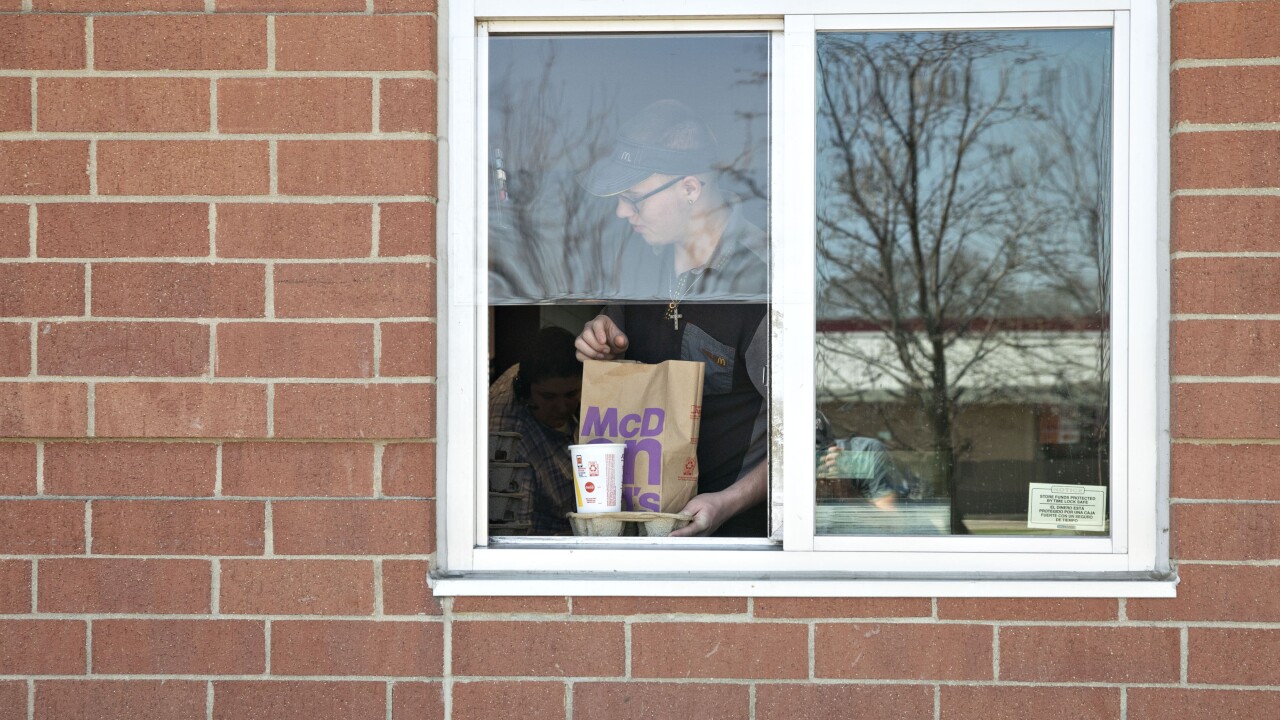 A McDonald's employee is handing out food in a drive-thru window.