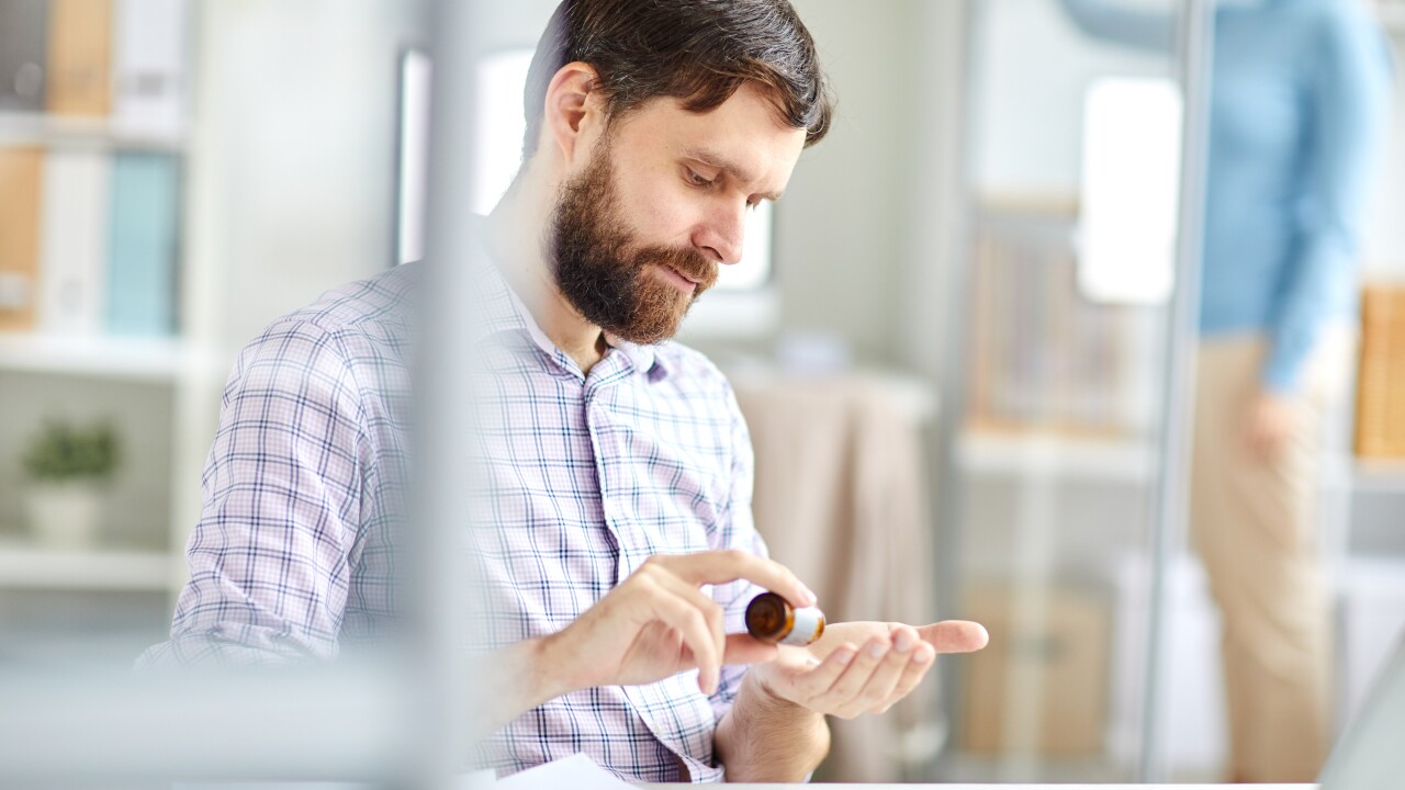 Man taking pills sitting at desk