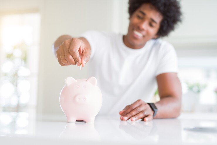 Man smiling putting money in piggybank