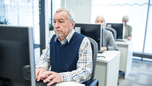 Active seniors attending computer course, working on PC