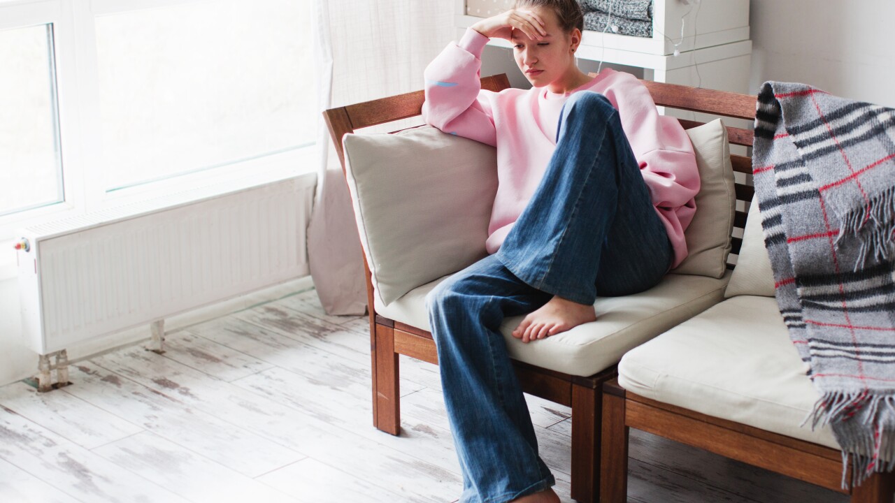 Sad young woman depressed sitting at home on the couch