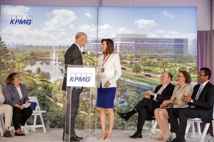 Florida Governor Rick Scott and KPMG CEO Lynn Doughtie, with a depiction of KPMG's upcoming facility in Orlando in the background