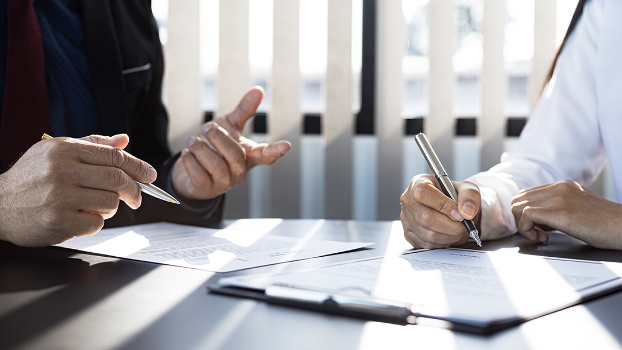 Two people at a table writing on paper forms