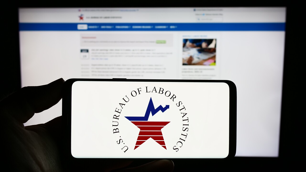 Stuttgart, Germany - 09-21-2023: Person holding mobile phone with logo of United States Bureau of Labor Statistics (BLS) on screen in front of web page. Focus on phone display.