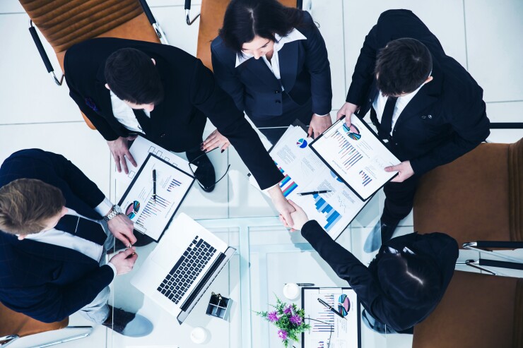 Office workers shaking hands and working together