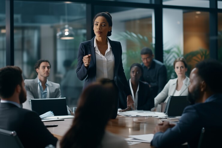 A black woman business leader dressed as an executive leading an important meeting as everyone looks on